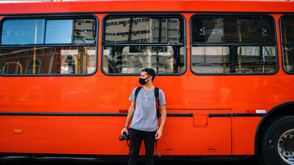 Traveler with a backpack watching familiar streets disappear from a bus or train window