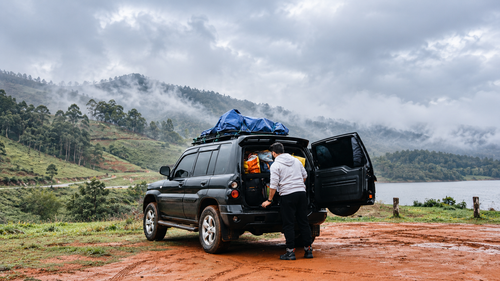 Road trip essentials packed neatly in a car trunk with travel documents, chargers, and a power bank.