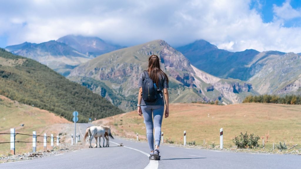 Traveler walking along a scenic road during a journey
