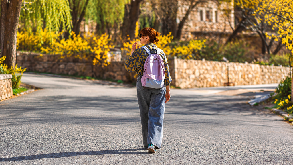 Traveler walking away with a backpack along a quiet residential street at dawn