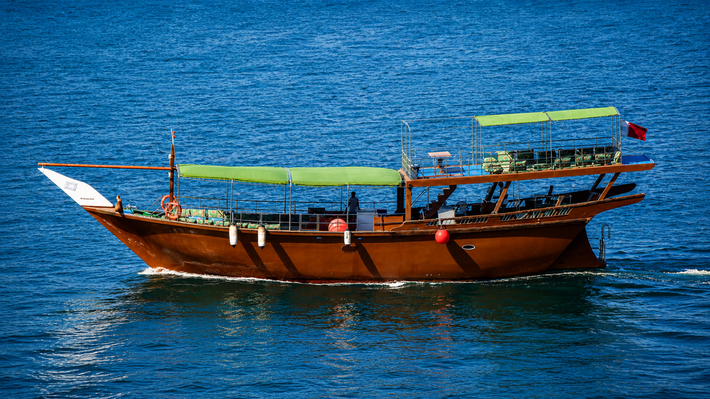 Traditional dhow sailing between Musandam cliffs Oman