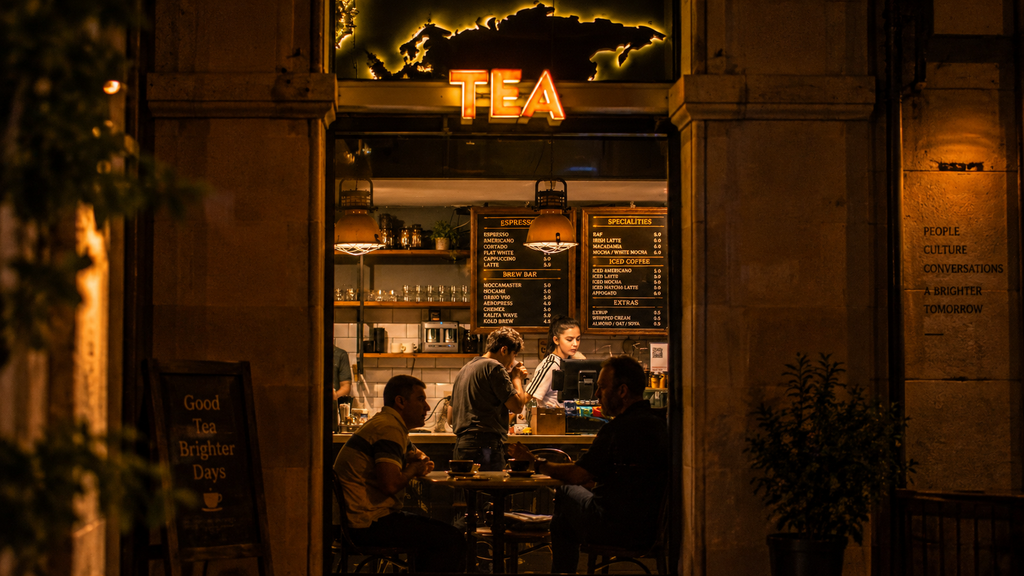 Cozy tea shop glowing at night with people inside