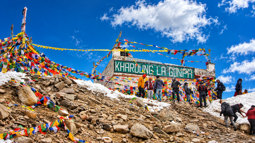  Khardung La pass signboard surrounded by high mountains and patches of snow in Ladakh.

